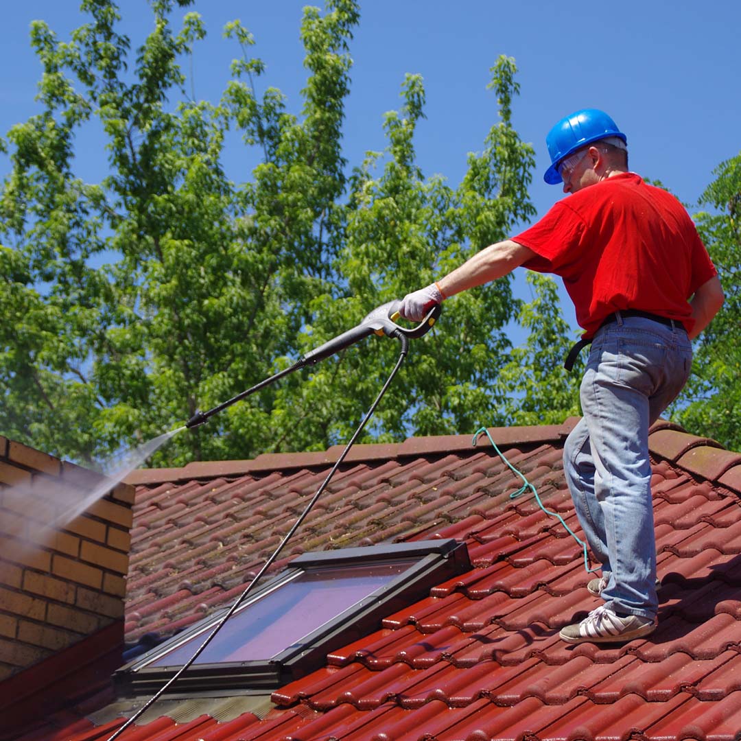 A worker hosing down a rooftop
