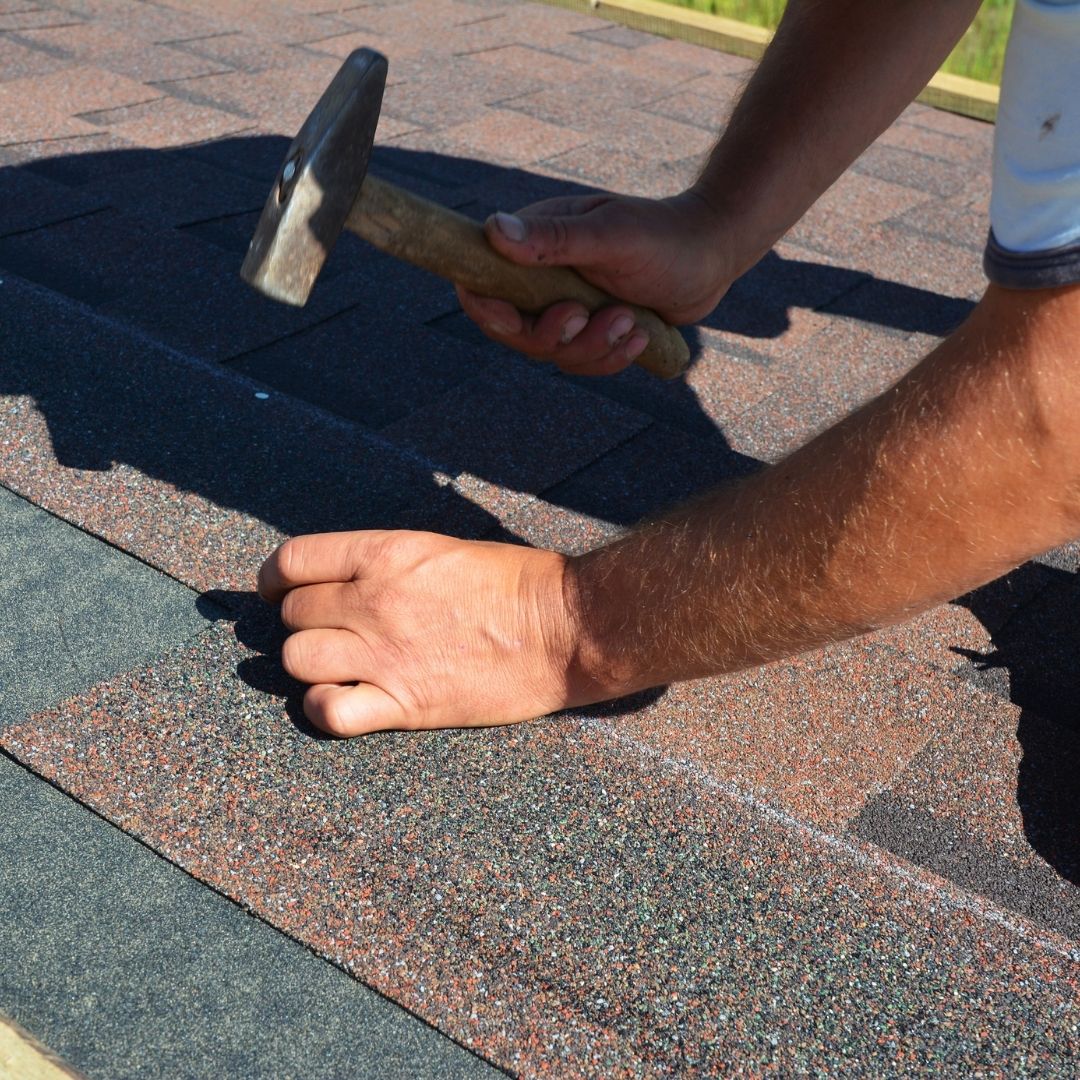 Man replacing shingles on roof