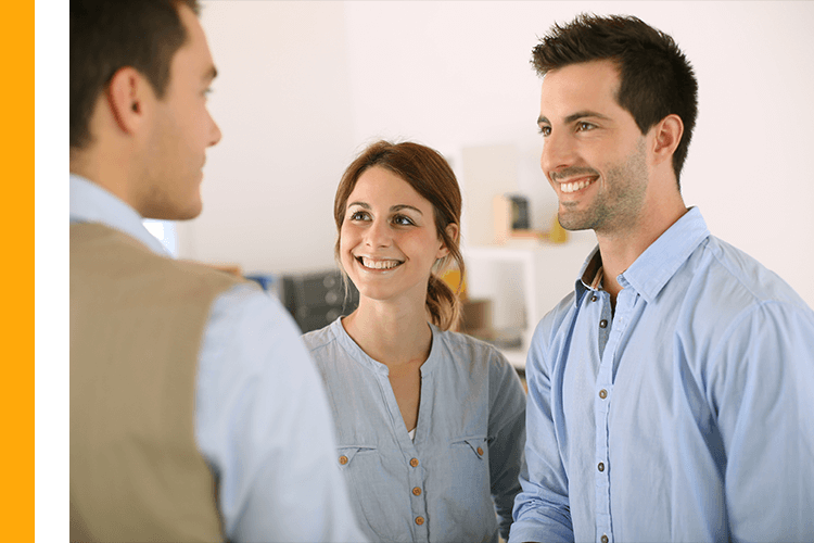 Couple smiling while talking to roofing professional in their home